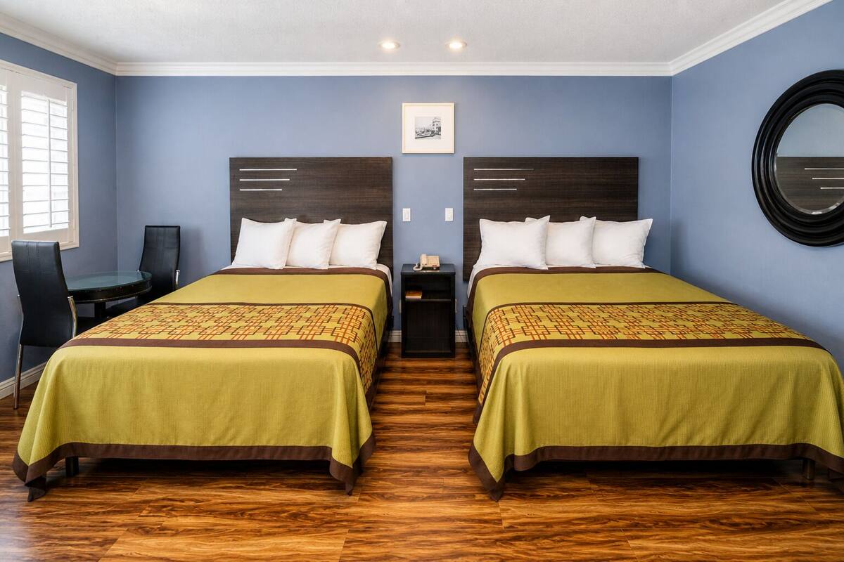 Habitación doble con dos camas, un escritorio y un espejo redondo.