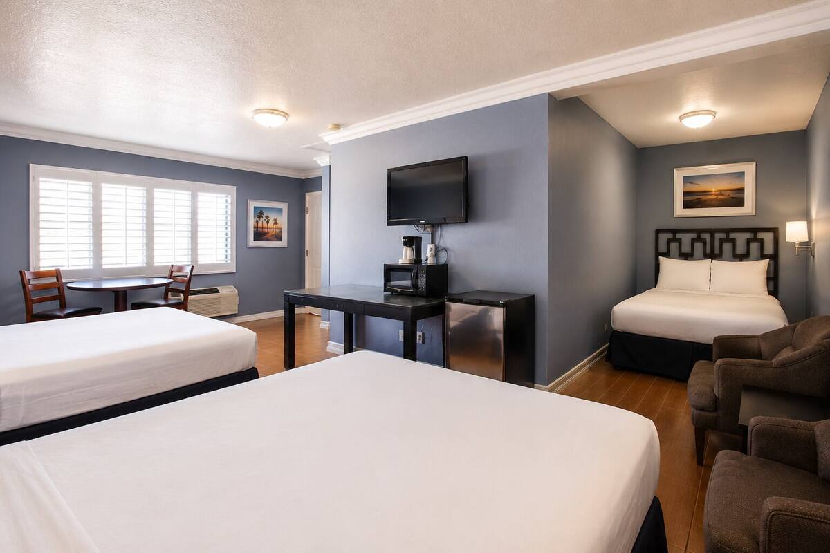 Habitación de hotel con dos camas, un escritorio, televisión, cafetera y refrigerador.