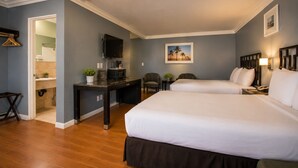 A hotel room with two beds, a desk with a TV, a small table, and a chair. - Big A Motel & Suites Near Disneyland Orange County (Orange)