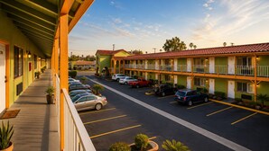 A motel with a covered walkway, multiple parking spaces, and a clear sky. - Big A Motel & Suites Near Disneyland Orange County (Orange)