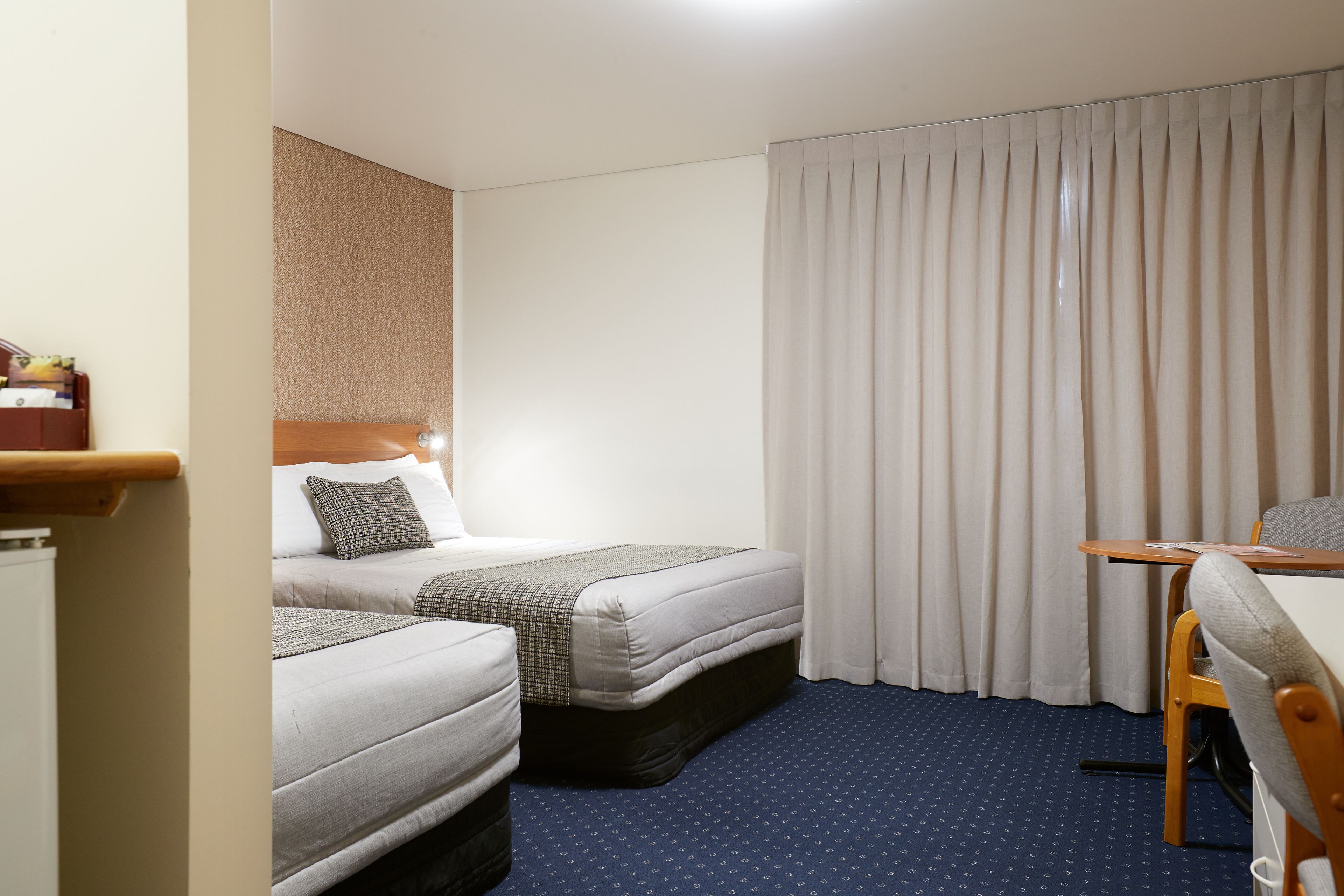 A hotel room with two beds, a desk, and a chair.