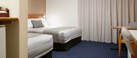 A hotel room with two beds, a desk, and a chair.