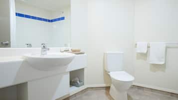 A modern bathroom with a white sink, mirror, and toilet.