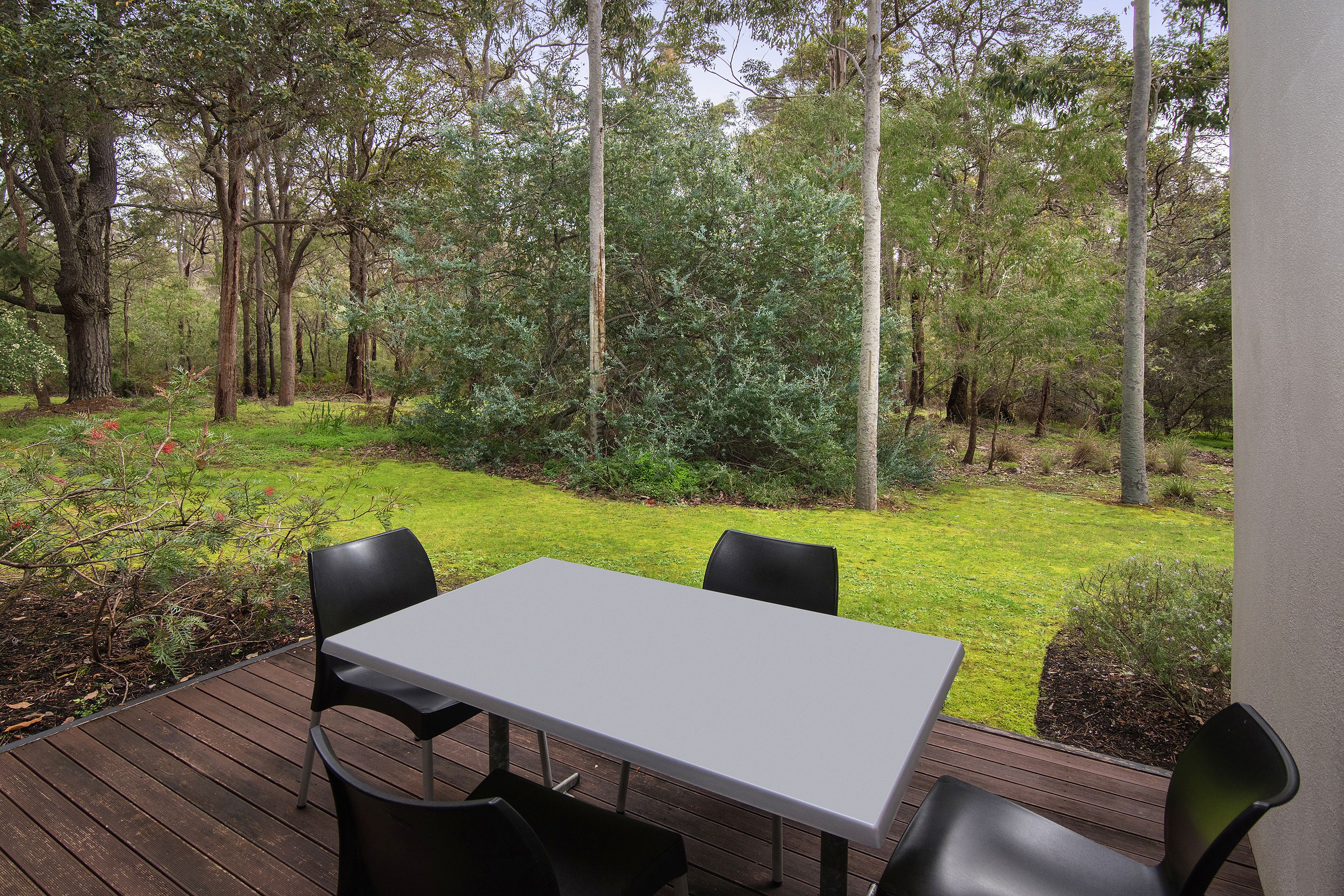 Una terraza con mesa y sillas que da a una zona boscosa.