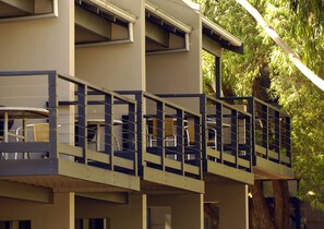 A multi-story building with a balcony area featuring wicker furniture and a chair. - Margarets Forest (Margaret River)