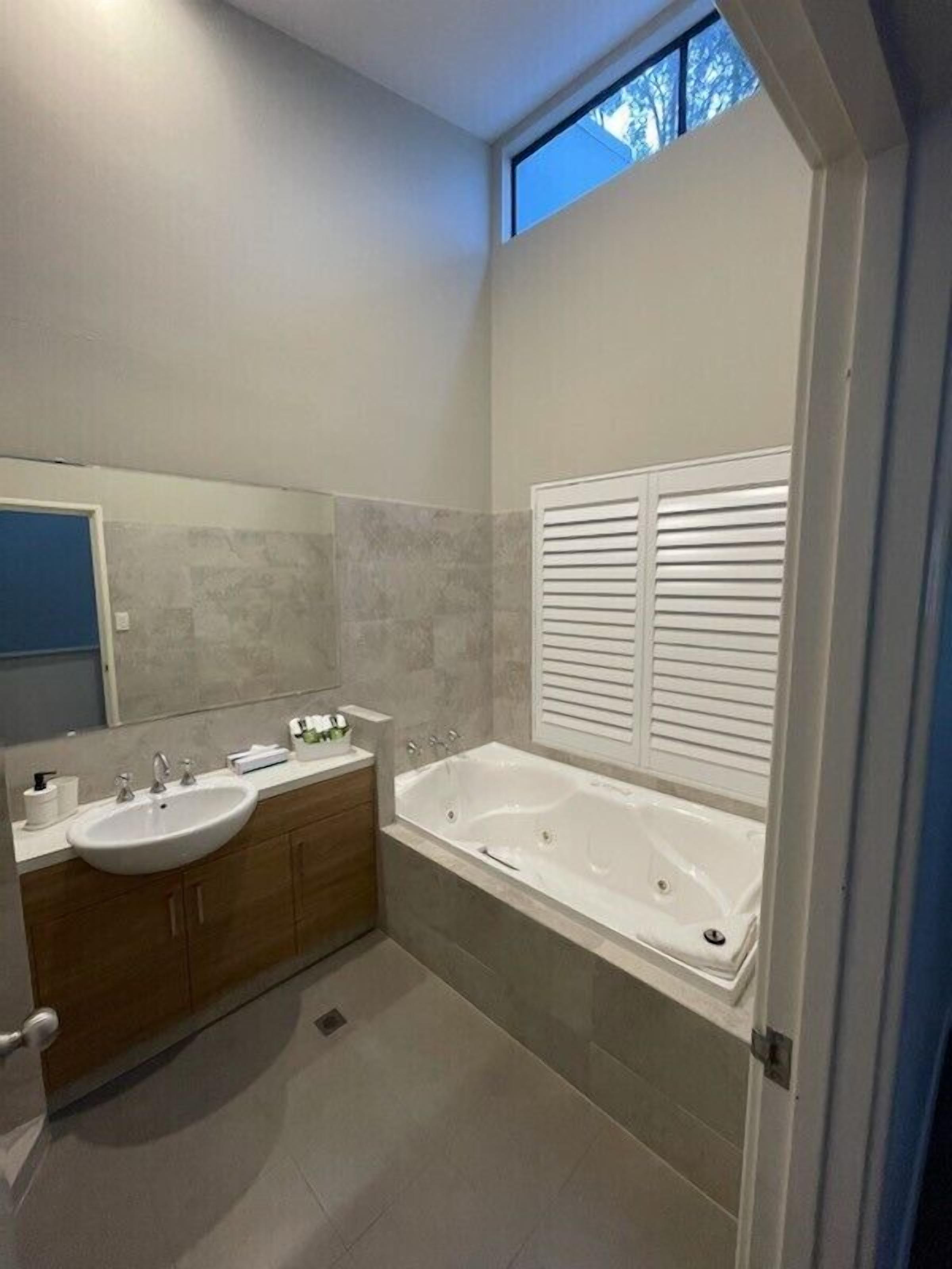 A modern bathroom with a double sink vanity, a freestanding bathtub, and a skylight.