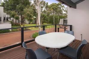 A balcony with a round table and four chairs, overlooking a street with trees and modern buildings. - Margarets Forest (Margaret River)