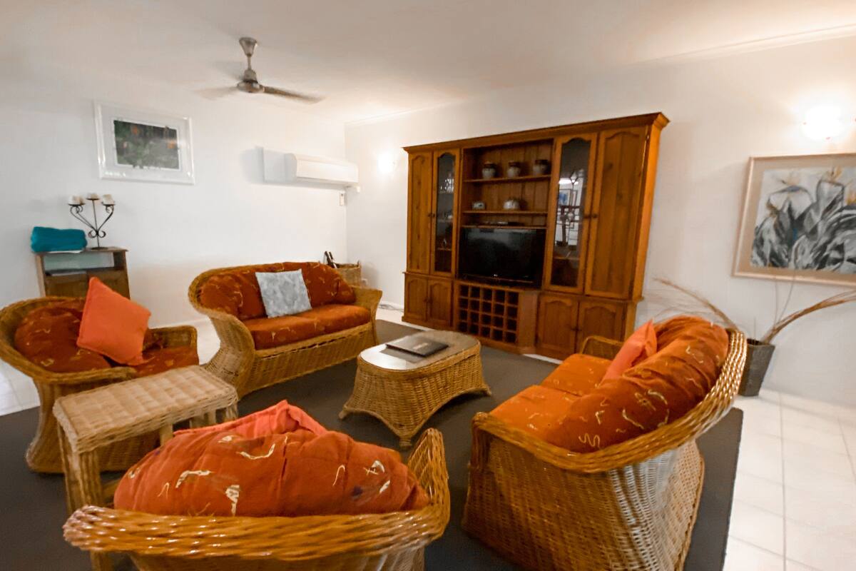 Ein Wohnzimmer mit Rattanmöbeln, einem Fernseher und einem Schrank.