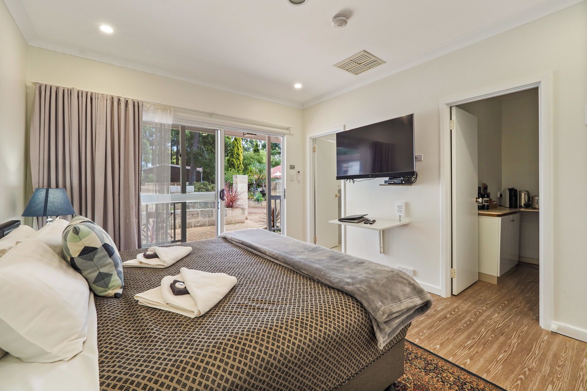 Habitación de hotel con cama, televisor, escritorio y vistas al exterior.