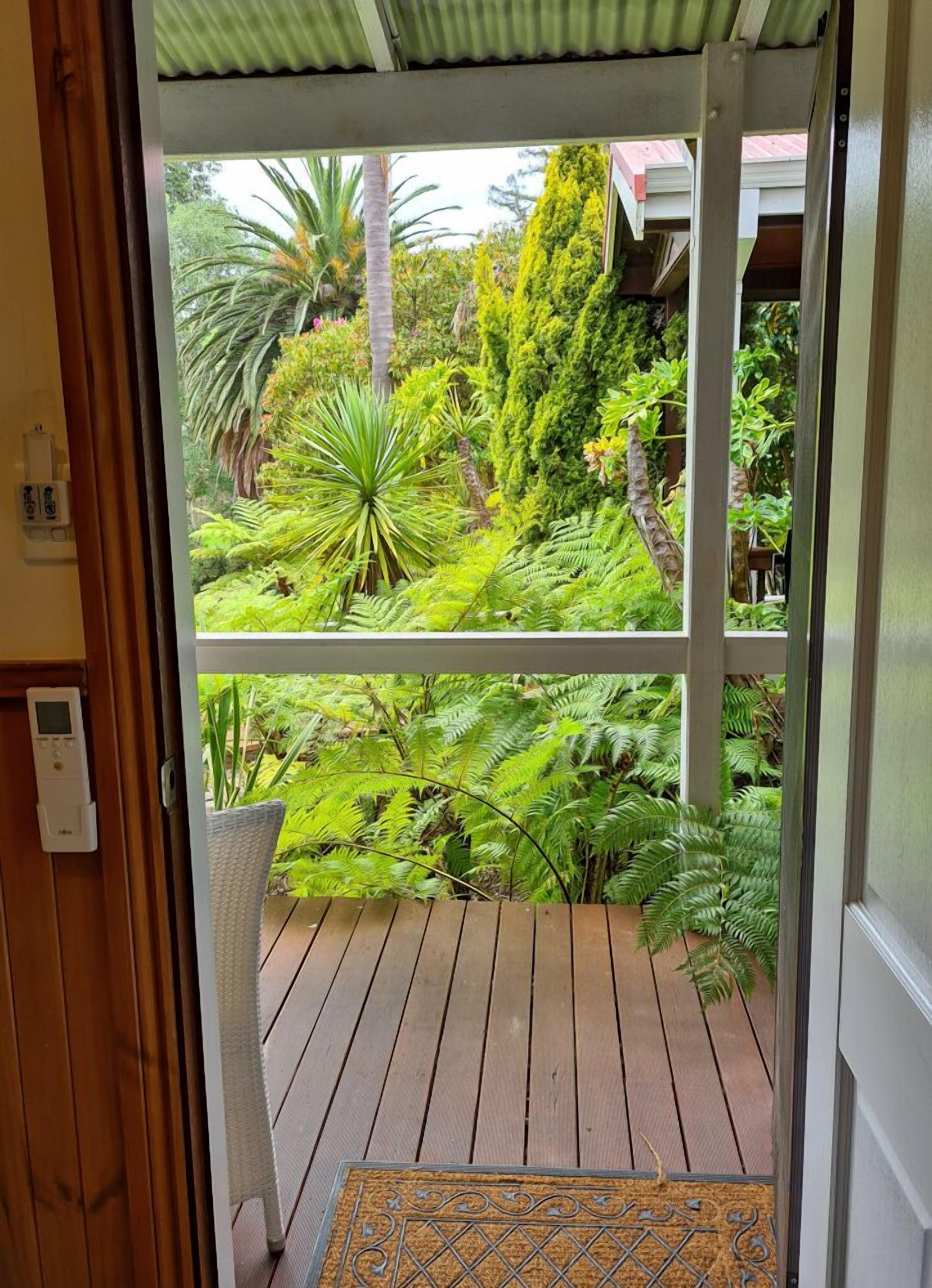 Une terrasse en bois offrant une vue sur un jardin luxuriant.
