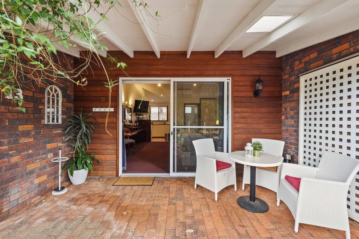 A cozy patio area with a brick wall, white wicker furniture, and a sliding glass door leading to an interior space.