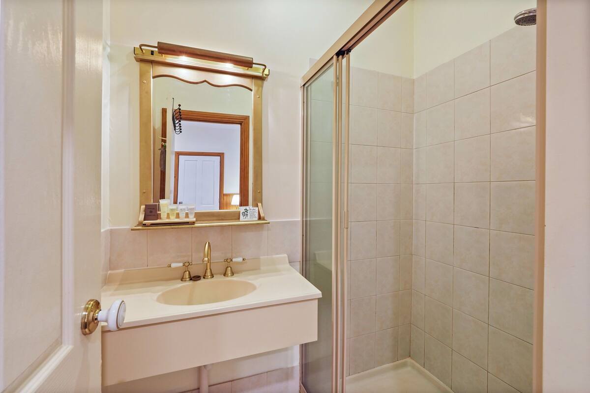 A bathroom with a white sink, a mirror, and a shower area.