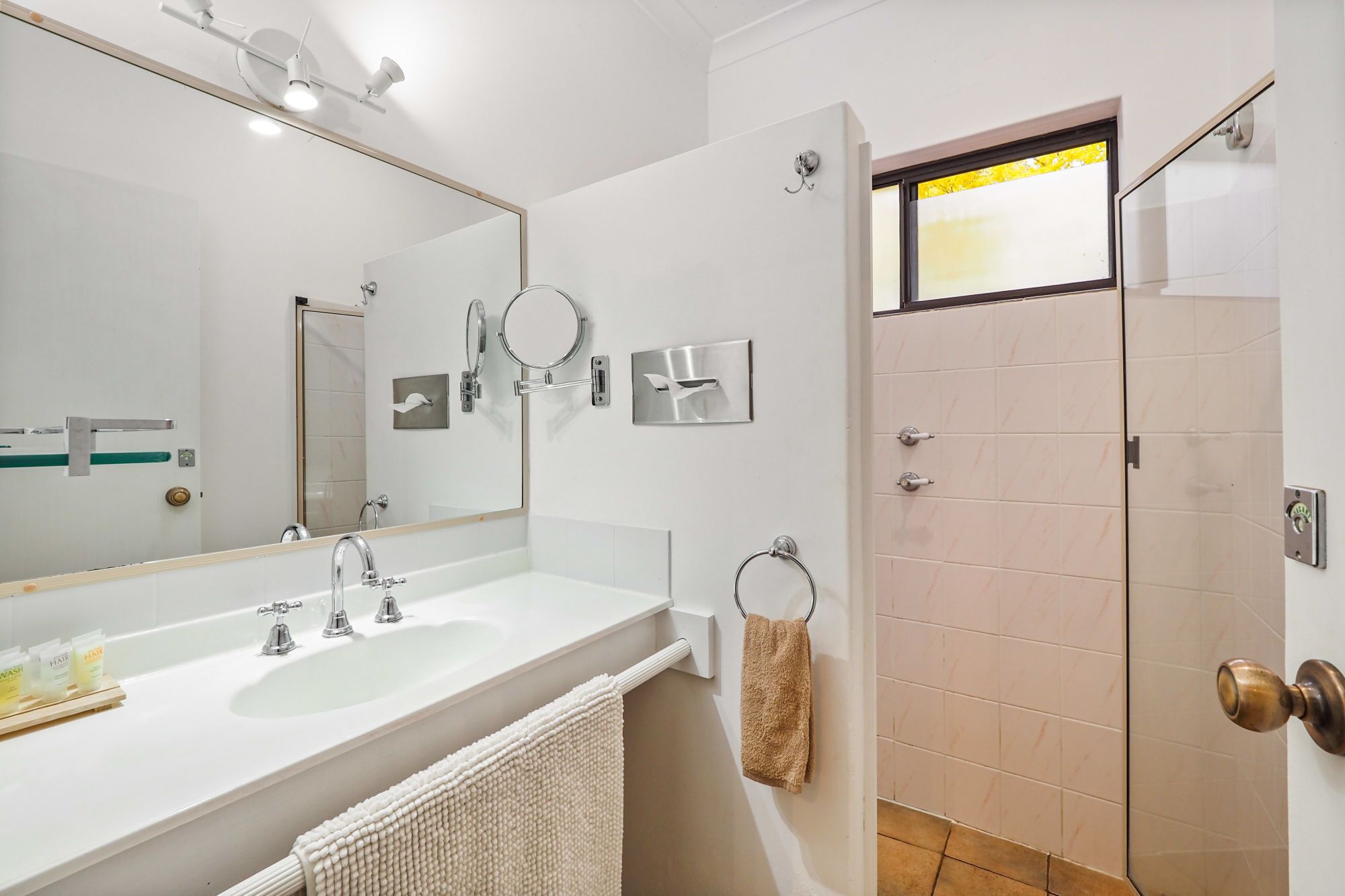 Un baño moderno con dos lavamanos, un espejo grande y una cabina de ducha con mampara de vidrio.