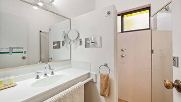 Un baño moderno con dos lavamanos, un espejo grande y una cabina de ducha con mampara de vidrio.