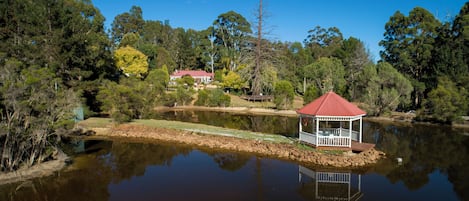 Ein Pavillon am See, mit einem Haus im Hintergrund.