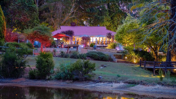 A lakeside restaurant with outdoor seating, surrounded by lush greenery and a pond. - Forest Lodge Resort (Pemberton)