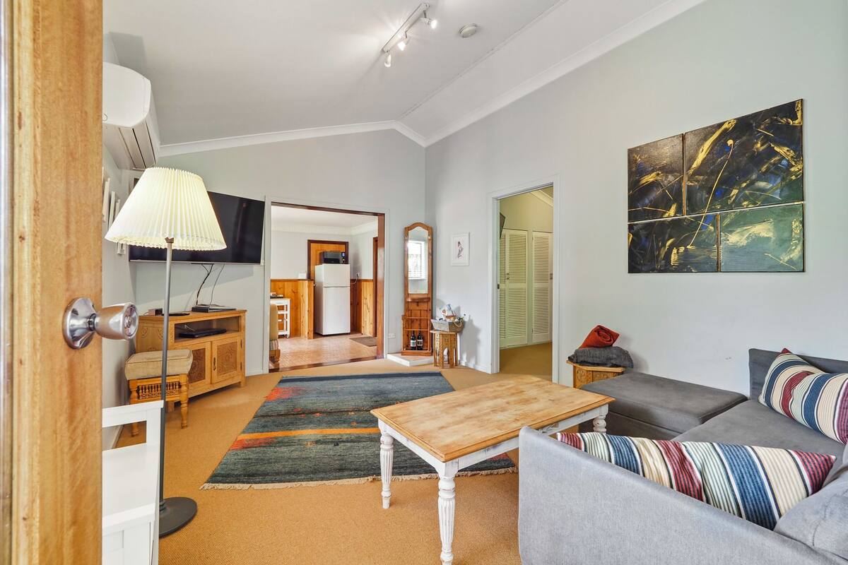 A spacious living room with a sofa, a wooden coffee table, and a television.