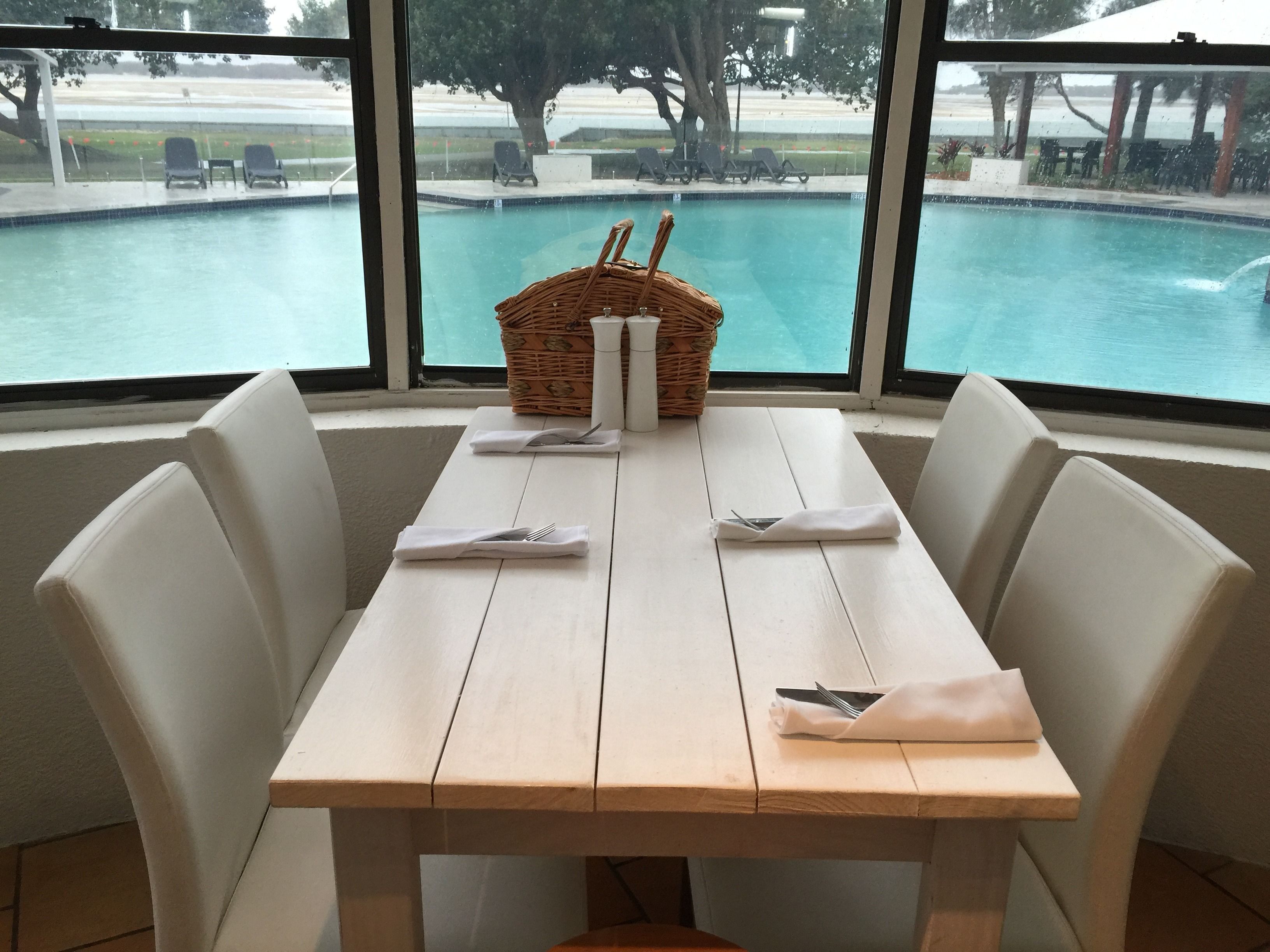 Een eettafel met witte stoelen en een mand met servetten en bestek.