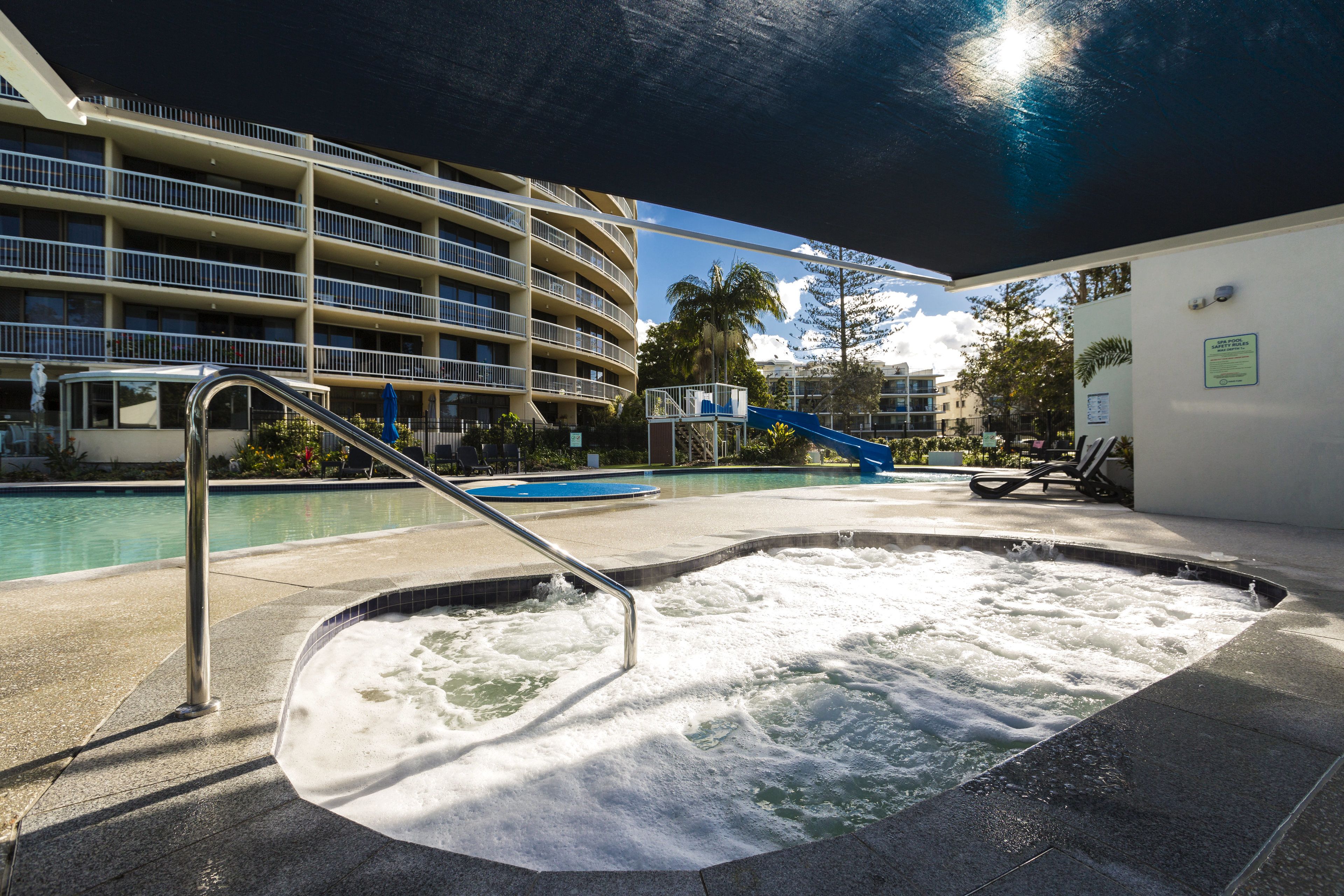Zona de banyera d'hidromassatge amb piscina i un edifici de diversos pisos al fons.