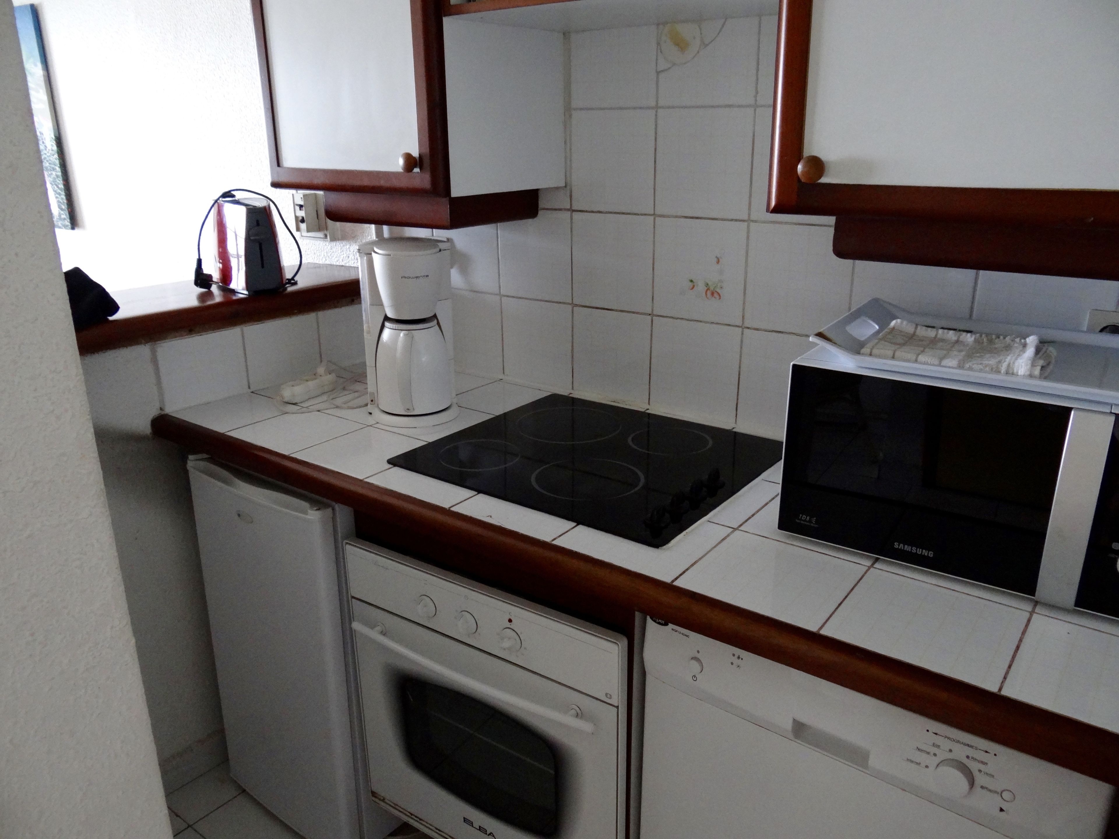 A compact kitchen with a built-in oven, a microwave, and a coffee maker on the countertop.