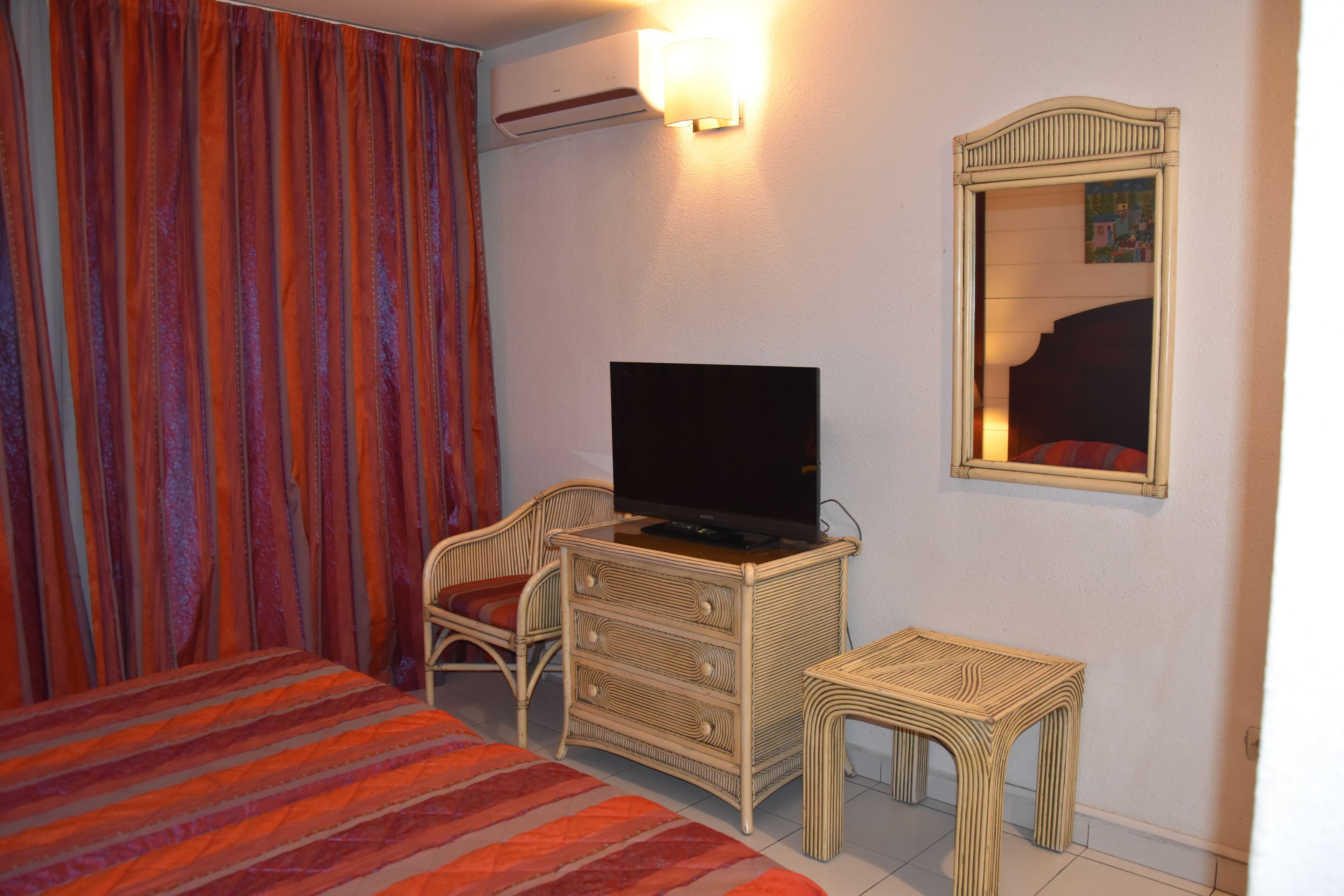 Una habitación de hotel con una cama, un televisor en una cómoda, una silla y una mesita.