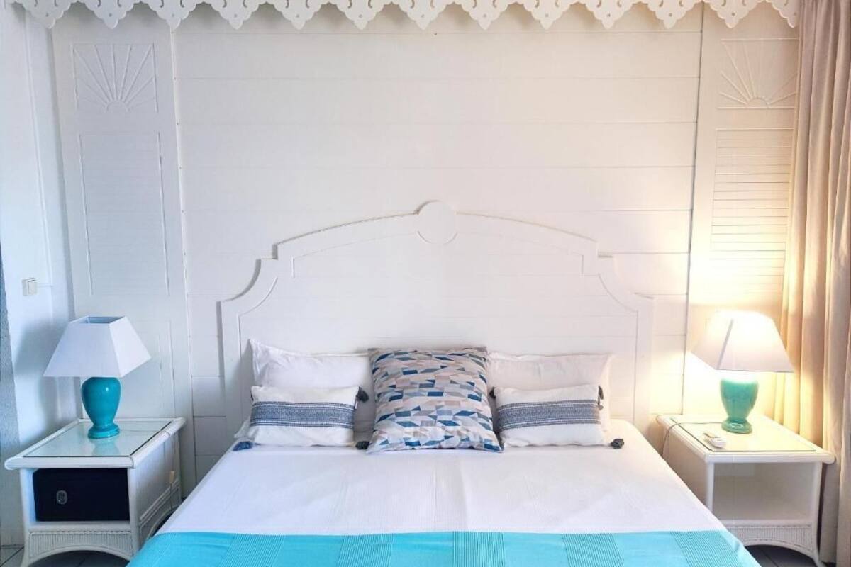 A neatly arranged bedroom with a white bed, matching nightstands, and a decorative ceiling.