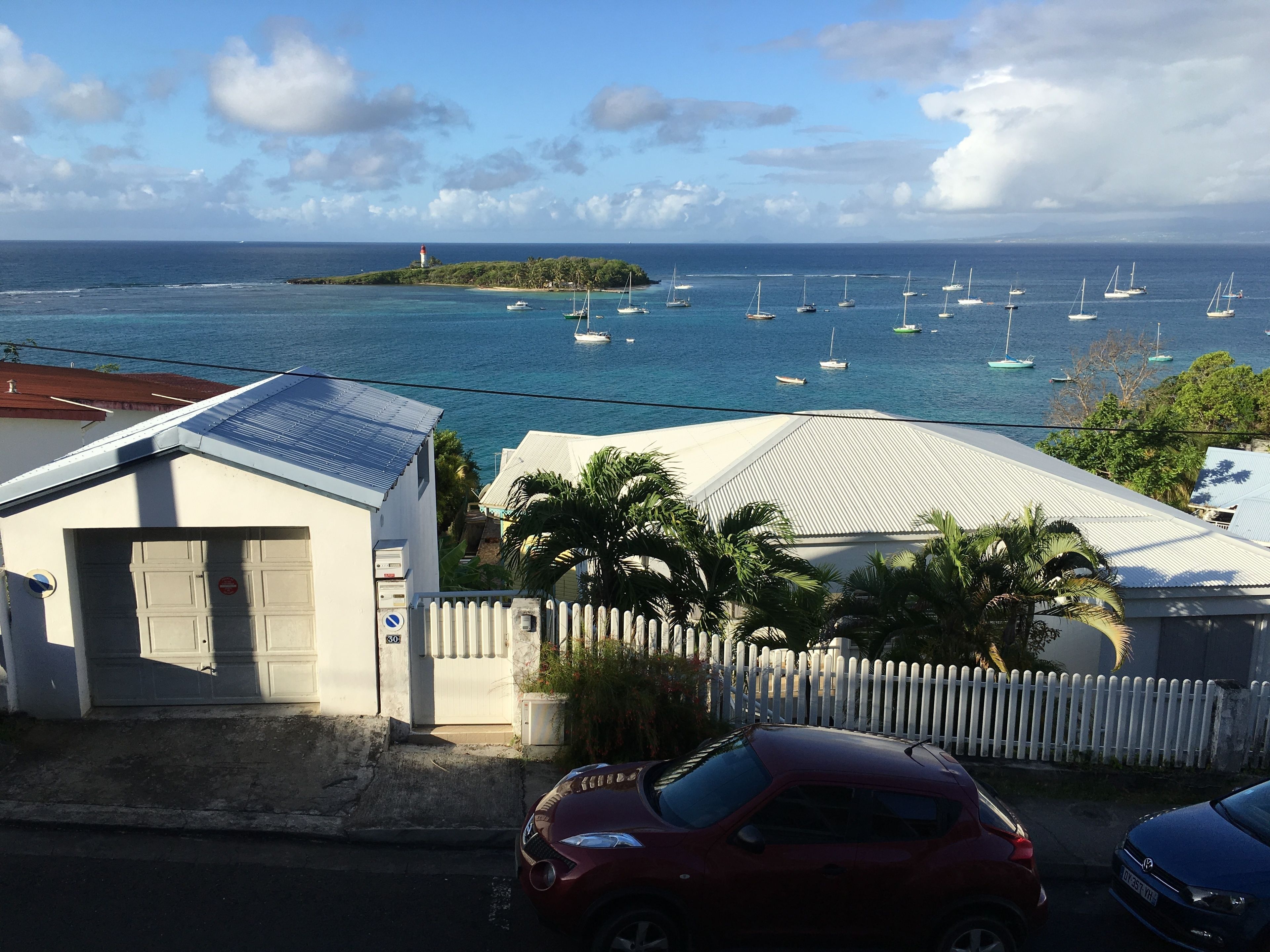 Une vue sur la côte, avec un port de plaisance, un phare et une petite île.