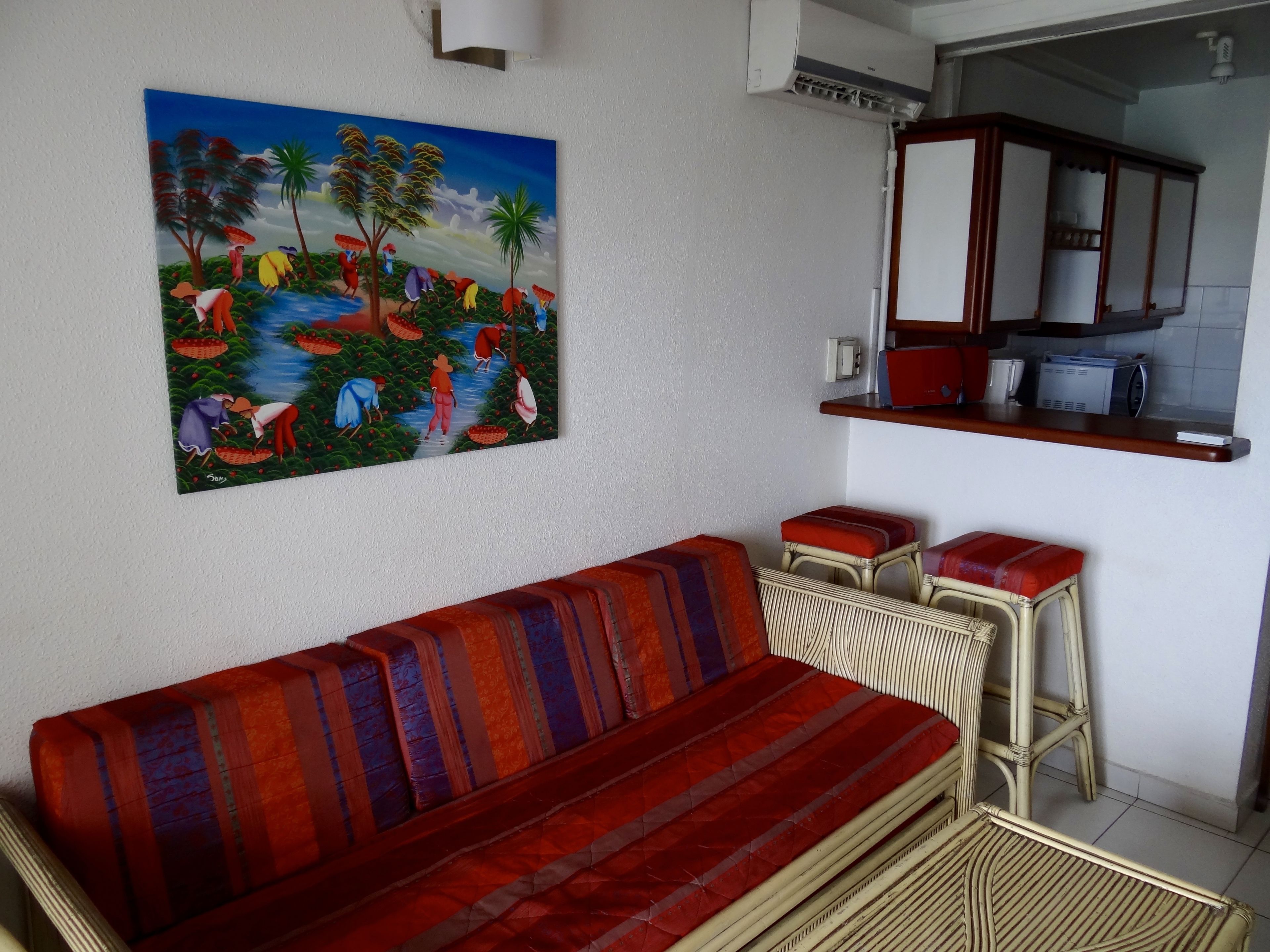 Un salon avec un canapé, un tableau et un coin cuisine.