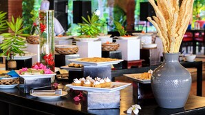 A buffet table with various food items and a vase with dried flowers. - Four Oceans Resort Muine (Mui Ne)