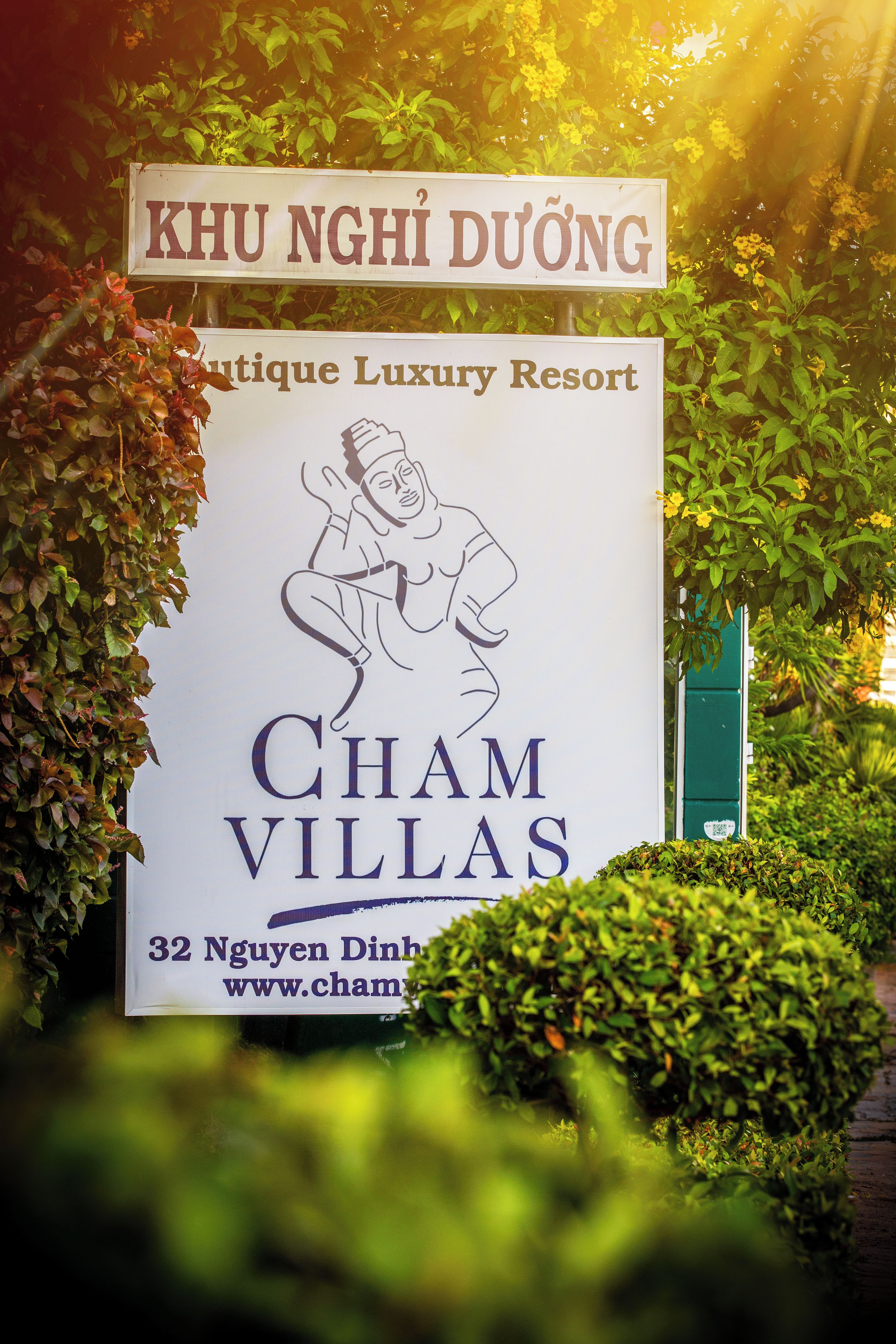 Une enseigne pour Cham Villas, un complexe hôtelier de luxe, avec une représentation stylisée d’un éléphant et un texte indiquant son emplacement et l’adresse de son site web.
