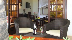 Un rincón de lounge de mimbre con dos sillones, una mesa y una botella de vino.