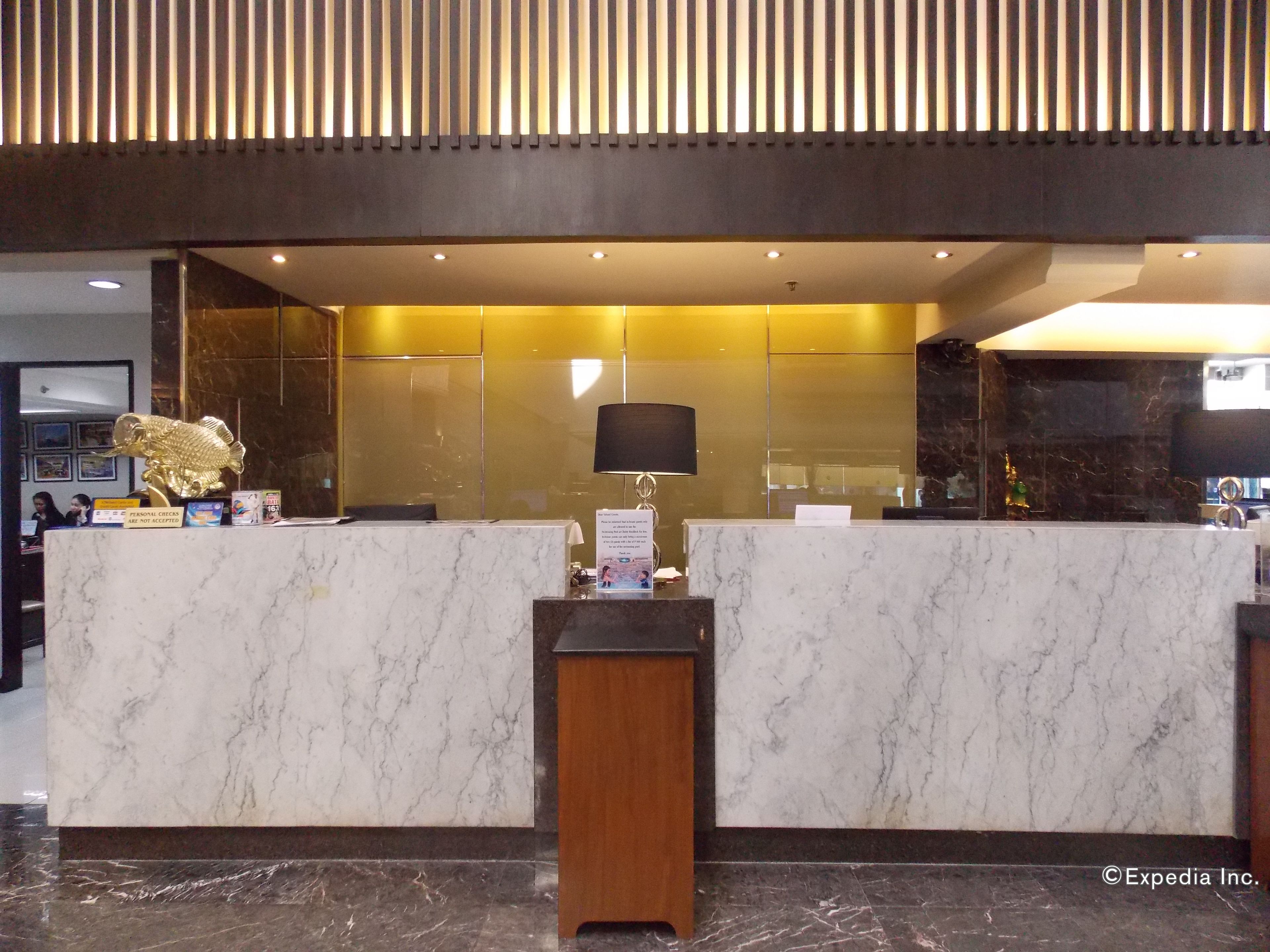 A reception desk with marble surfaces and a wooden base, a black lamp, and a gold decorative piece.