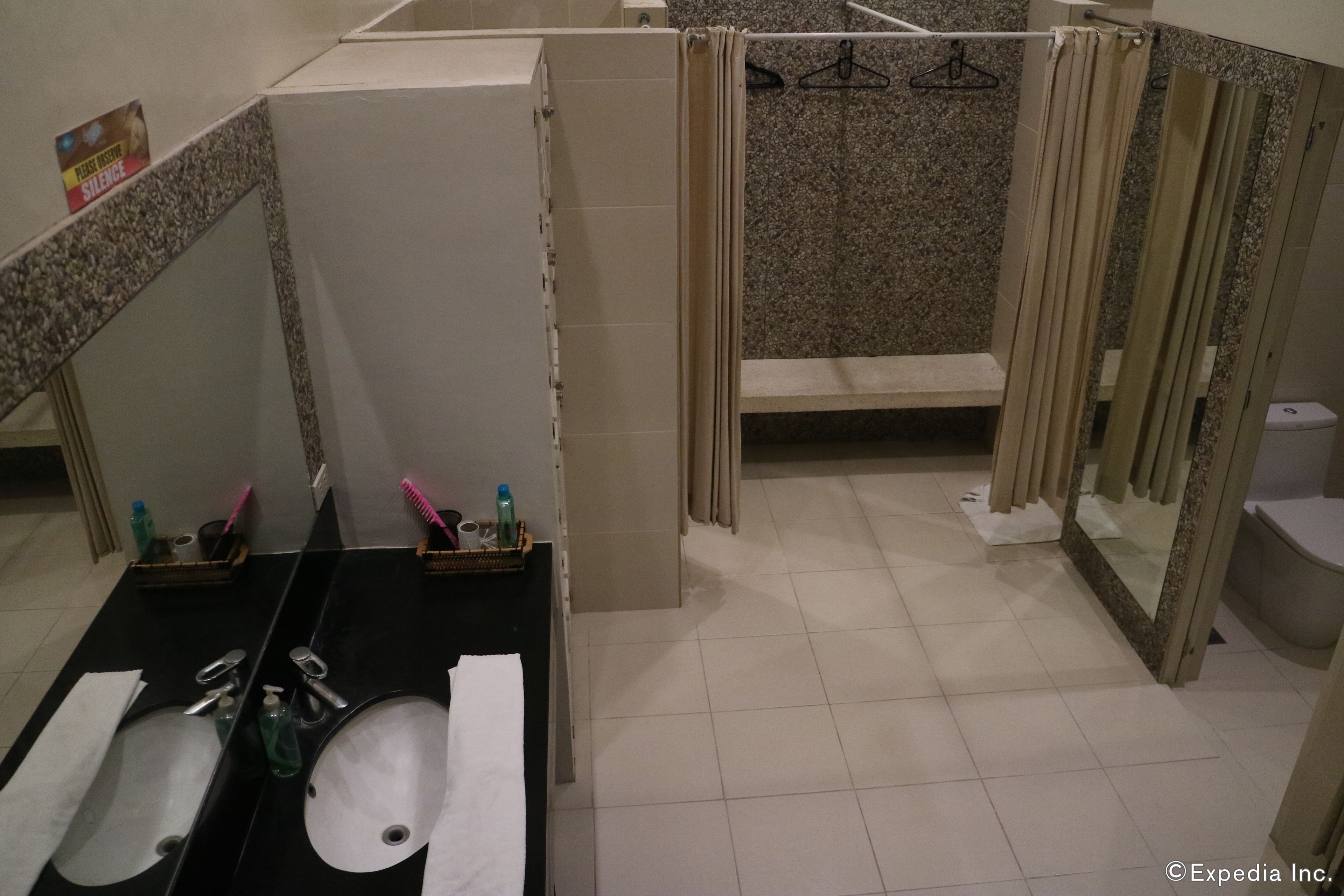A bathroom with two sinks, a mirror, a shower area, and a toilet.