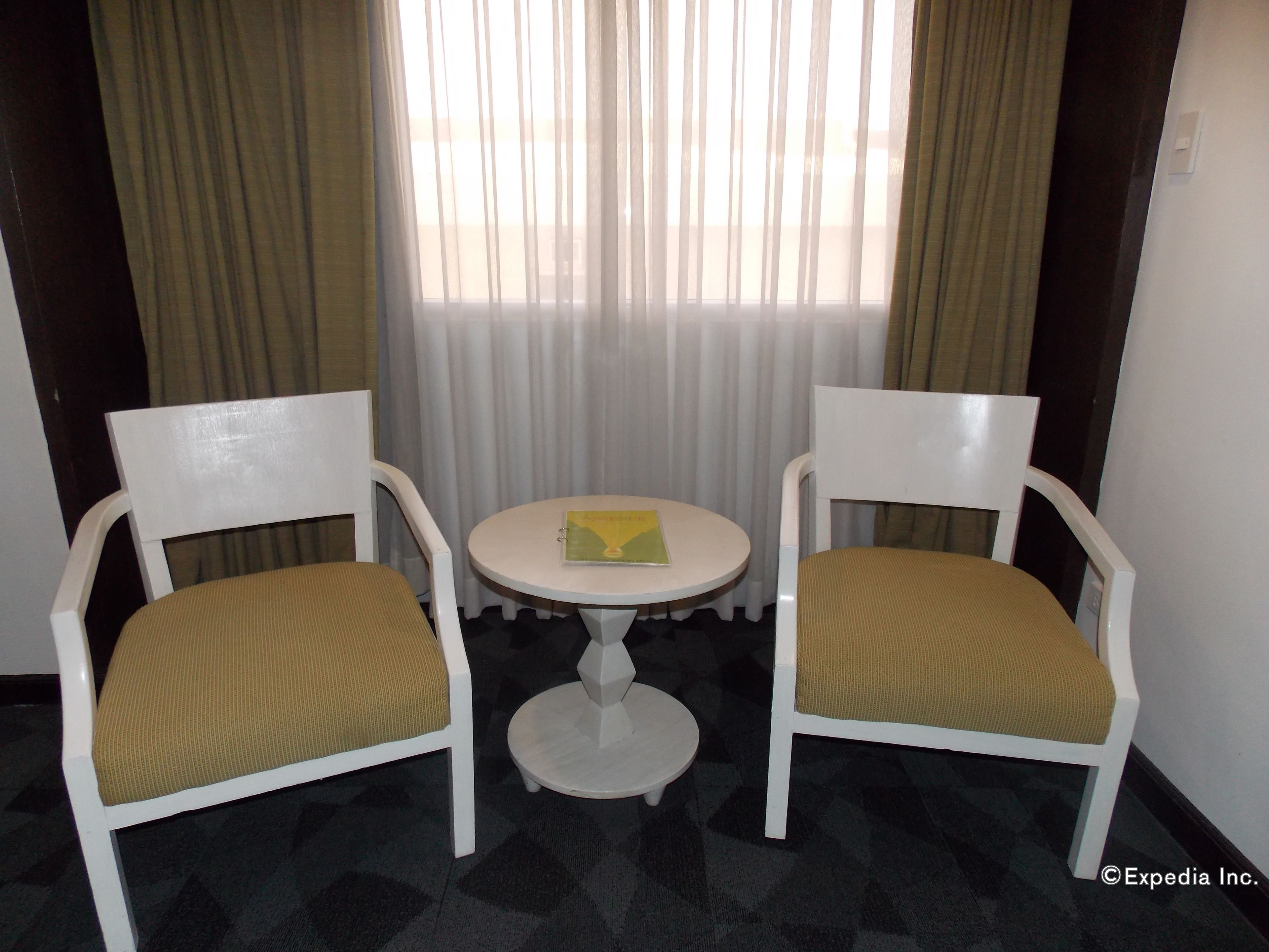 Two white chairs with brown cushions and a small white table with a book between them.
