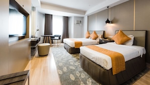 Une chambre d’hôtel avec deux lits, un bureau, une chaise et une petite table.