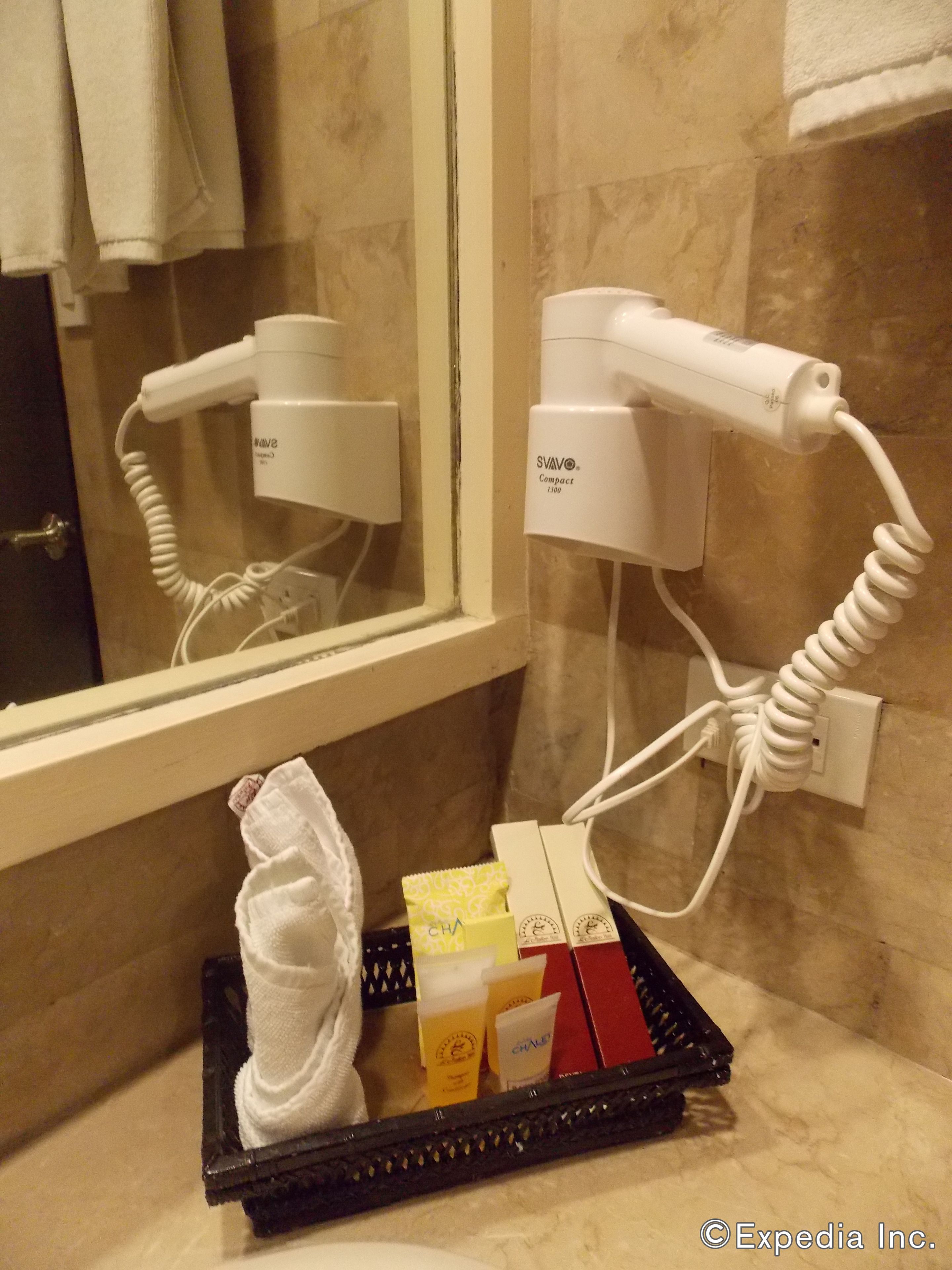 A bathroom with a hairdryer, a towel, and toiletries on a tray.