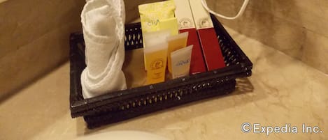 Un baño con secador de pelo, toalla y artículos de aseo en una bandeja.