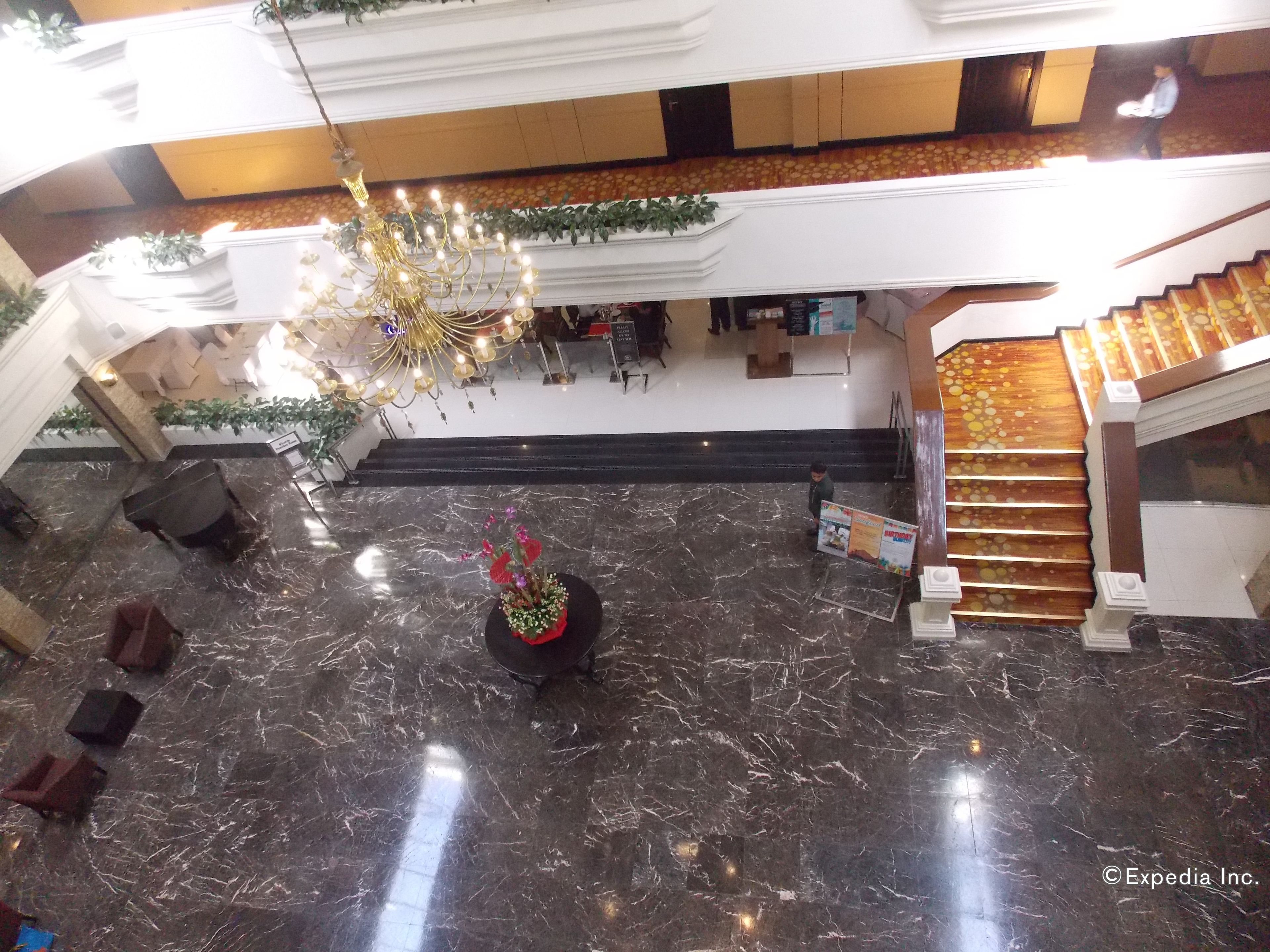 A lobby with a marble floor, a chandelier, a staircase, and a reception desk.