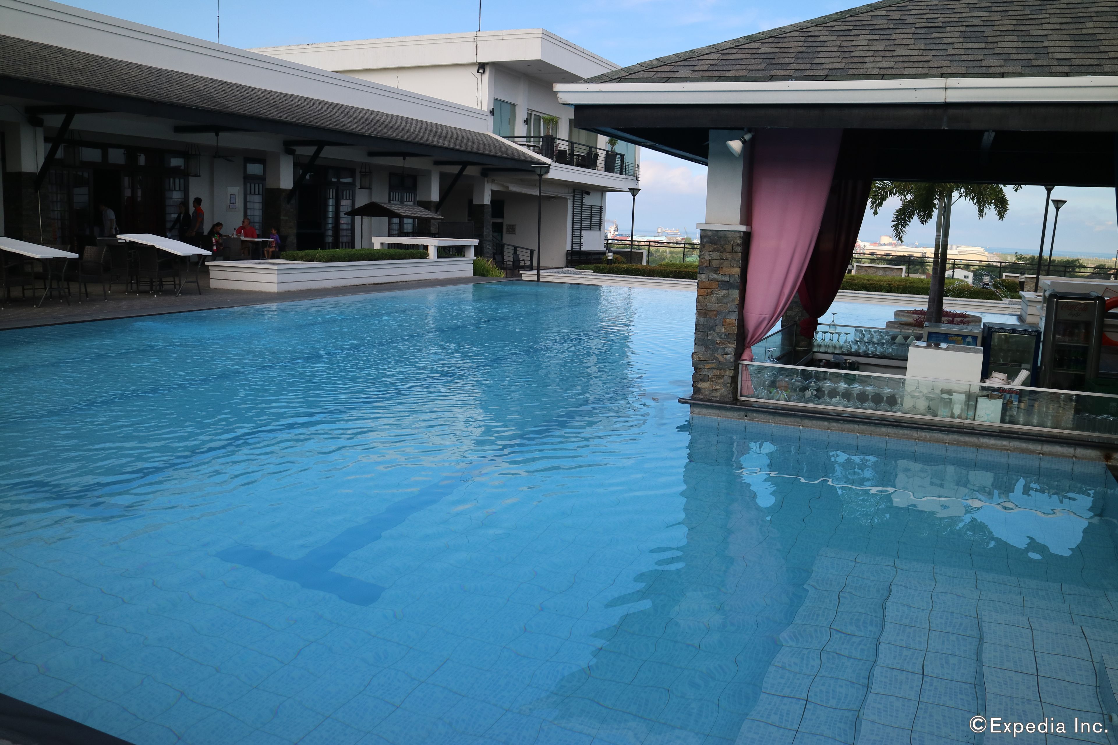 A swimming pool with a covered area, a bar, and a view of the sea.