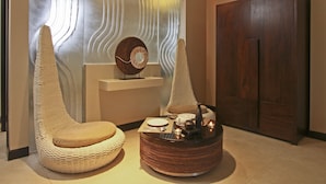 A modern interior with a round coffee table, two wicker chairs, a decorative wall panel, and a wooden wardrobe. - Two Seasons Boracay Resort (Boracay Island)