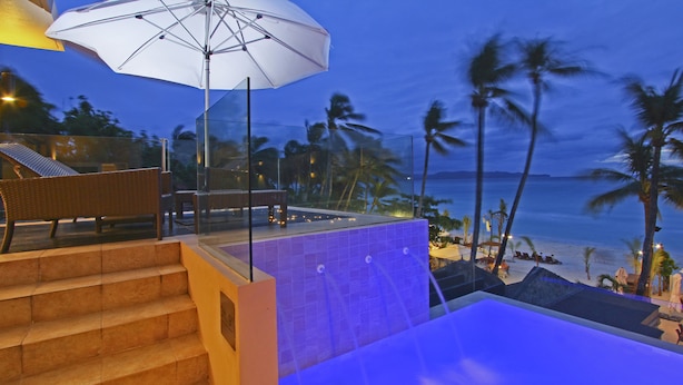 A pool area with a glass balustrade, a white umbrella, and a view of the beach and palm trees. - Two Seasons Boracay Resort (Boracay Island)