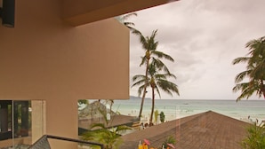 A covered outdoor seating area with wicker chairs and a table, overlooking a beach with palm trees and the ocean. - Two Seasons Boracay Resort (Boracay Island)