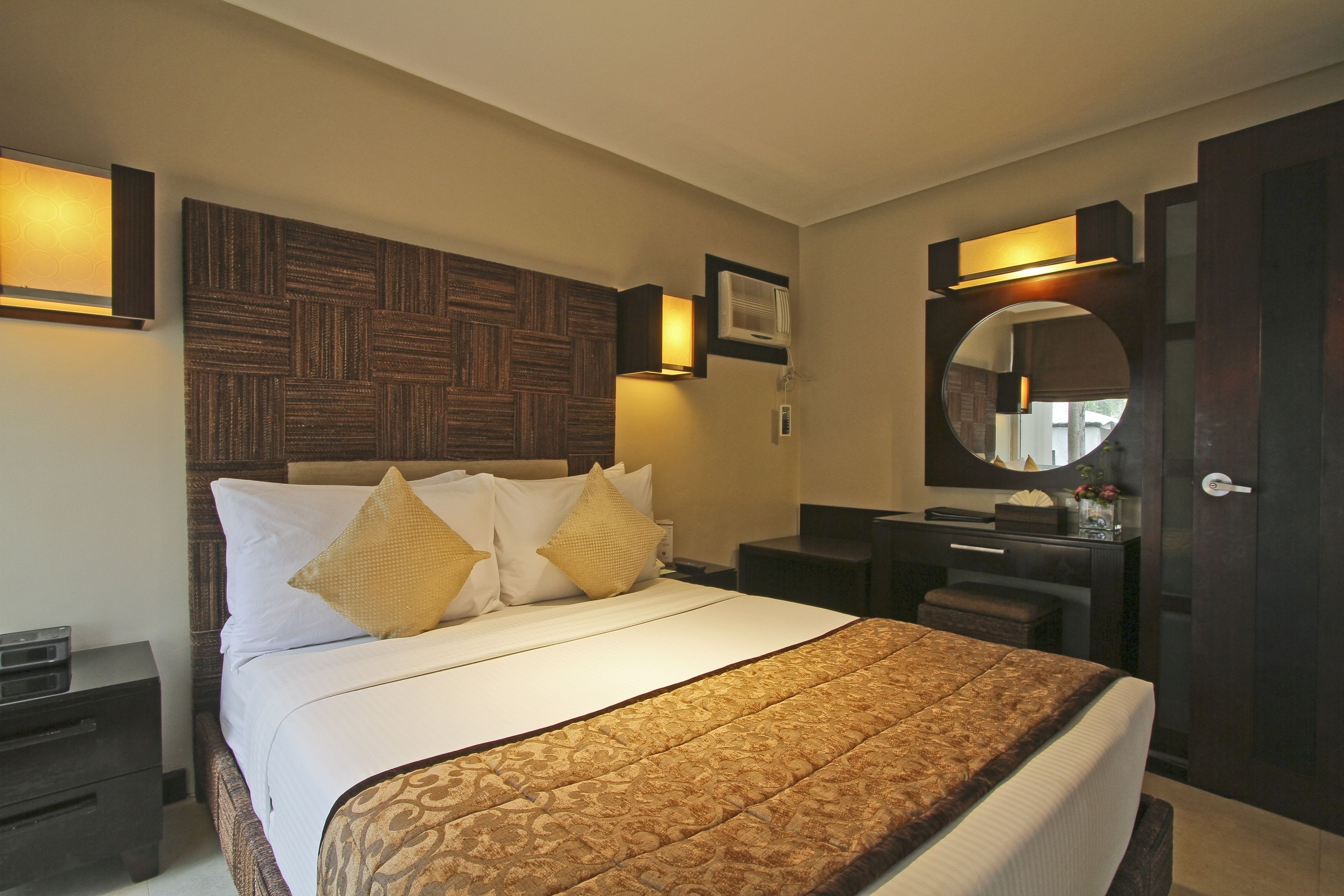 Een hotelkamer met een groot bed, een nachtkastje, een dressoir en een spiegel.