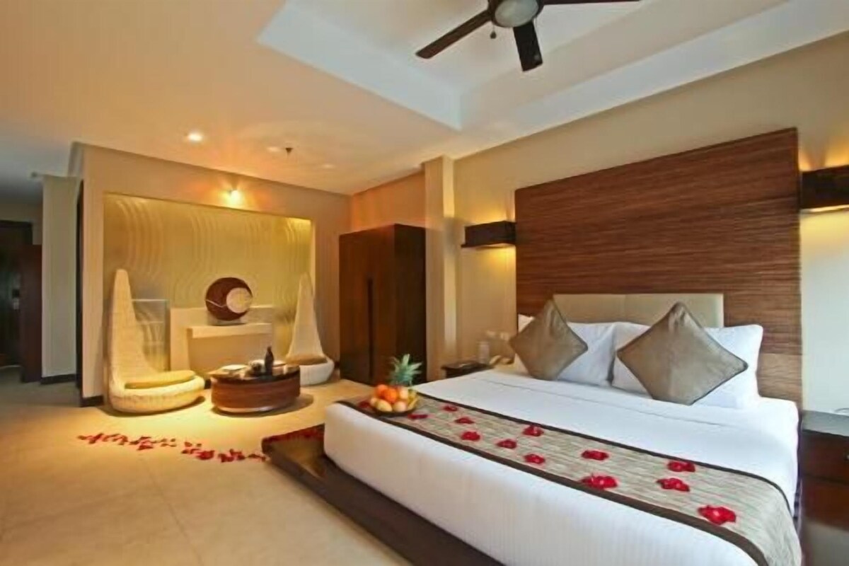Una habitación de hotel con cama, mesita de noche y ventilador de techo.