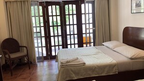 Una habitación de hotel con cama, una silla y vistas a través de un ventanal.