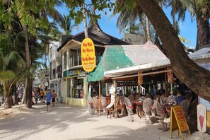 A beachfront restaurant with outdoor seating and a signboard advertising 'Nigi Nigi Nu Noos Beach Resort'. - Nigi Nigi Nu Noos “e” Nu Nu Noos (Boracay Island)