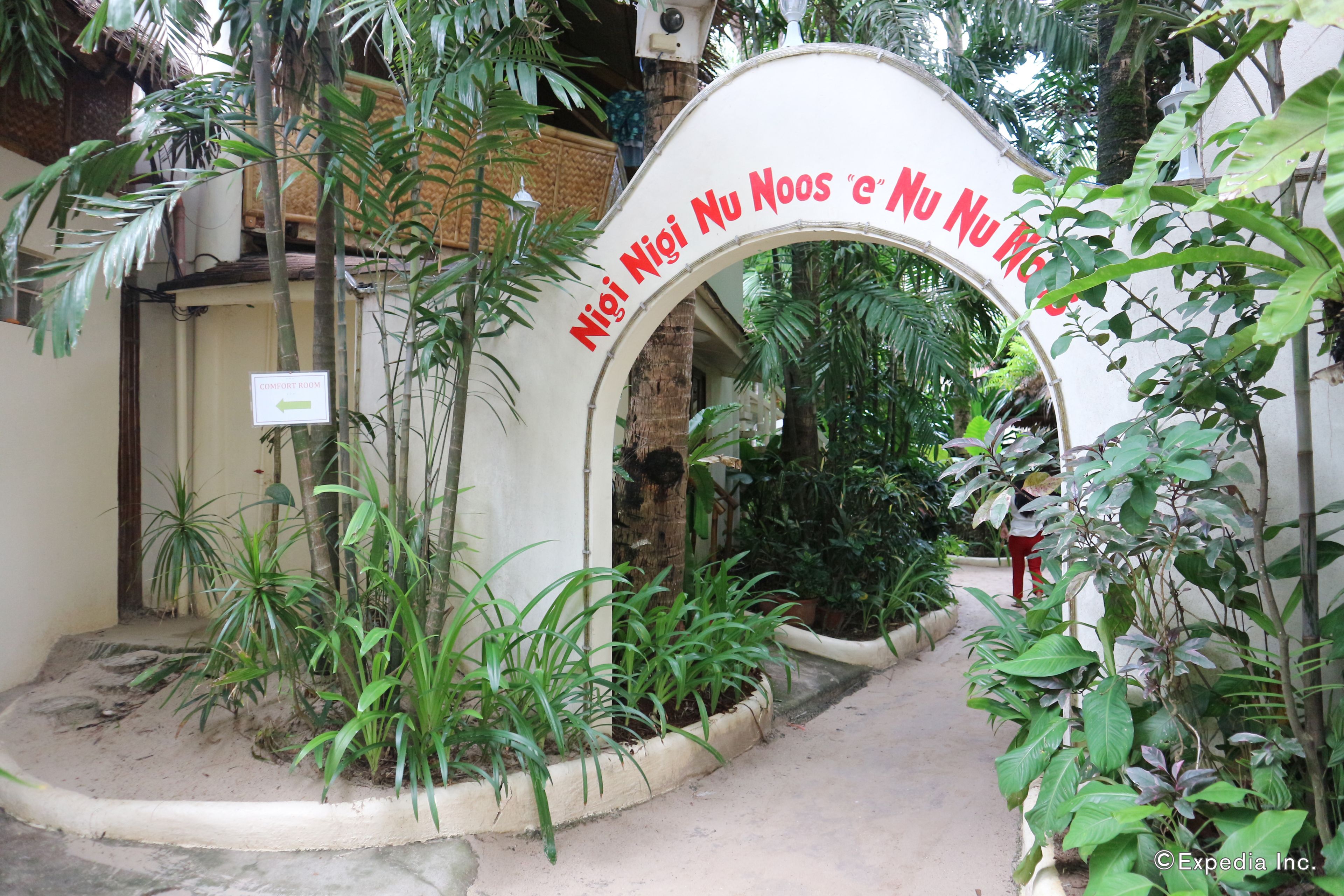 An archway with a sign reading "Niig Nigi Nu Noos e Nu Nu Noos" leading to a building entrance.