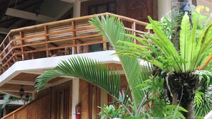 A two-story building with a thatched roof, wooden balconies, and a lush garden with various tropical plants. - Nigi Nigi Nu Noos “e” Nu Nu Noos (Boracay Island)