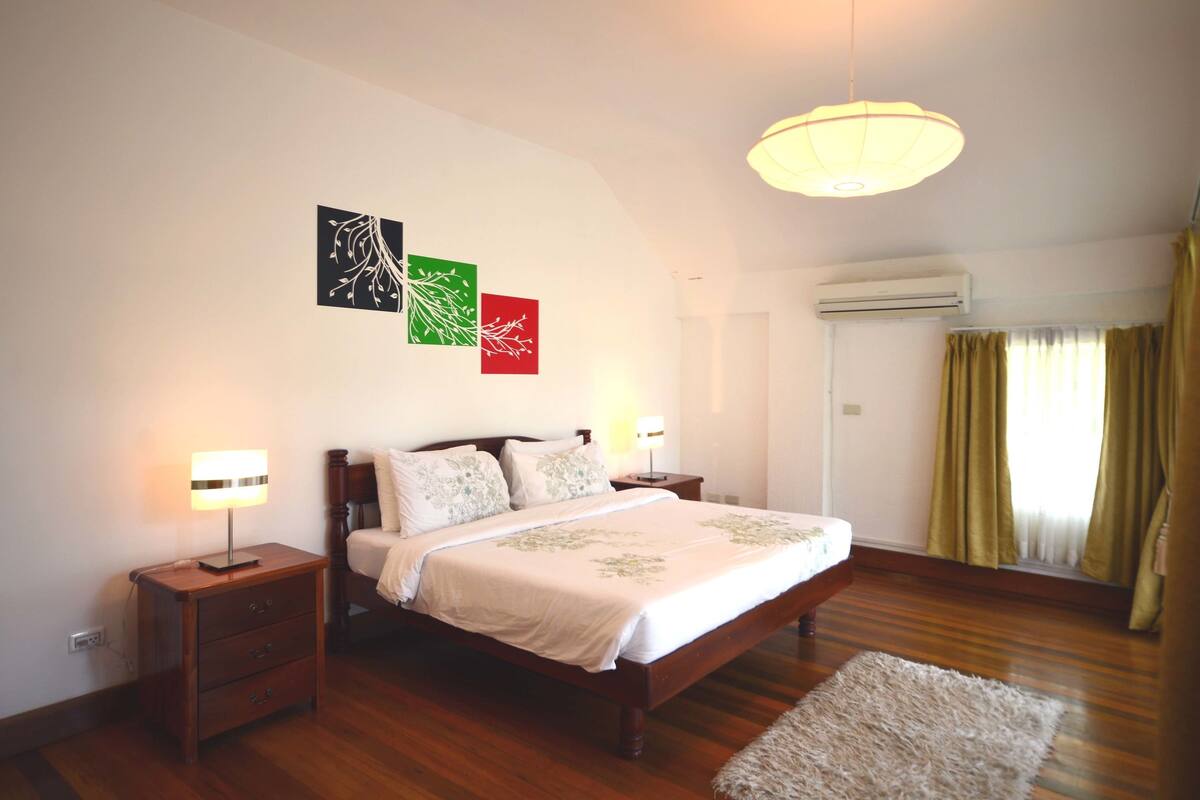 Un dormitorio con cama de madera, mesitas de noche, lámpara colgante y decoración en la pared.