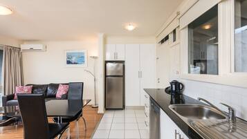 A modern kitchen with white cabinets, a stainless steel refrigerator, and a black countertop.